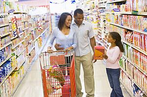 Mother and father with young daughter shopping at the grocery store.