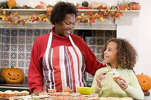 Grandmother and granddaughter making Halloween treats and smiling