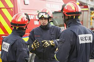 Three rescue workers talking by rescue vehicle