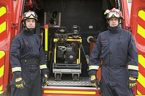 Two rescue workers standing by open back door of rescue vehicle