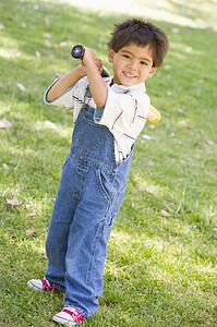 Young boy holding baseball bat outdoors smiling