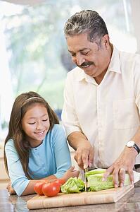 Grandfather And Granddaughter Preparing meal, mealtime Together