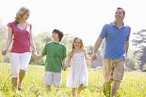 Family walking outdoors holding flower smiling