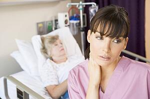 Nurse Standing In Hospital Room, Looking Tired