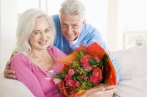 Husband and wife holding flowers and smiling
