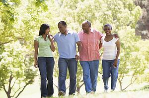 Two couples walking outdoors arm in arm smiling