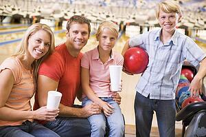 Family in bowling alley with drinks smiling