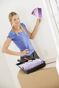 Woman with paint swatches in new home smiling