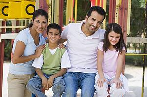 Family sitting on playground structure smiling (selective focus)