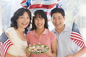 Family outdoors on fourth of July with flags and cookies smiling