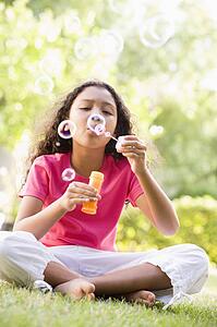 Young girl blowing bubbles outdoors