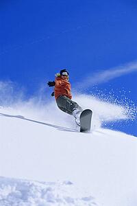 Snowboarder coming down snowy hill smiling