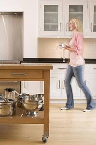 Woman walking in kitchen holding coffee