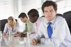 Four businesspeople in a boardroom writing