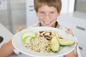 Young boy in kitchen eating rice fruit and nuts smiling