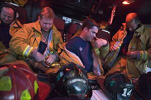Four firemen in fire engine putting on gear (blur)