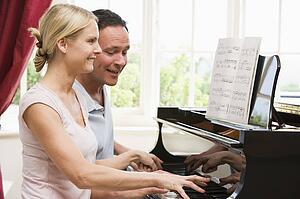 Couple playing piano and smiling