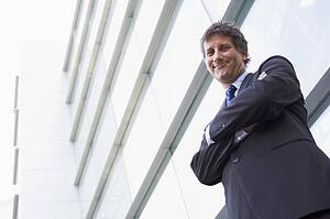 Businessman standing outdoors by building smiling