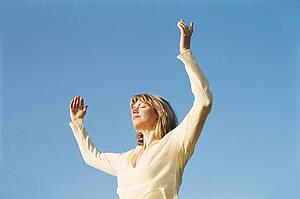 Woman standing outdoors with arms up