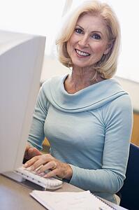 Woman sitting at computer typing (high key)