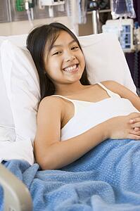 Young Girl Smiling, Lying In Hospital Bed