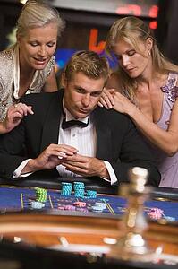 Three people in casino playing roulette smiling (selective focus)
