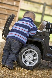 Young boy playing outdoors with toy truck
