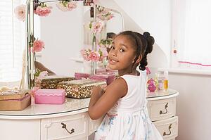 Young girl sitting at mirror in bedroom smiling