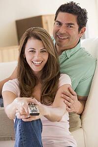 Couple in living room with remote control smiling