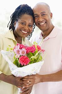 Husband and wife holding flowers smiling