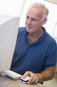 Man at computer smiling and looking at monitor (high key)