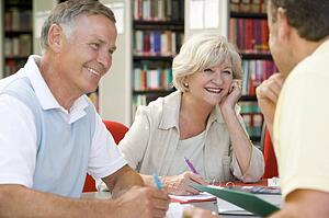 Three people in library writing in notebooks (selective focus)