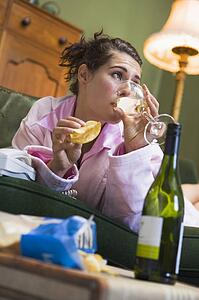 Young woman at home drinking wine and eating potato chips