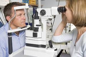 Optometrist in exam room with man in chair