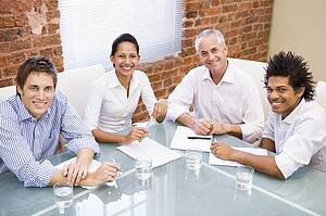 Four businesspeople in boardroom smiling