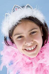 Young girl wearing crown and feather boa smiling