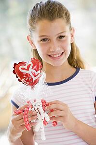 Young girl on Valentine's Day holding love themed balloon smiling