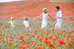 Family walking in poppy field holding hands smiling