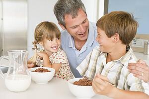 Father Sitting With Children As They Eat Breakfast 