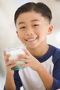 Young boy indoors drinking milk smiling