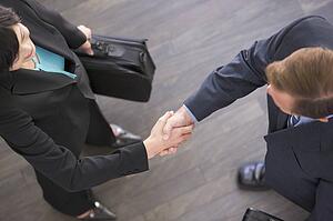 Two businesspeople standing indoors shaking hands