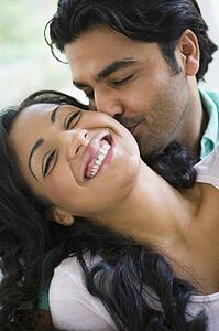 Couple in living room embracing and smiling (high key)