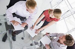 Three businesspeople in boardroom with paperwork