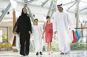 Family walking in mall holding hands and smiling (selective focus)