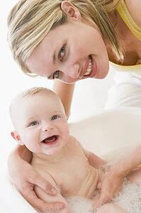 Mother giving baby bubble bath smiling