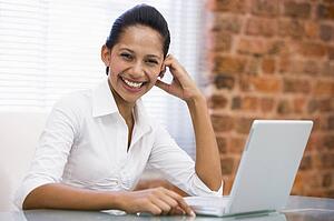 Businesswoman in office with laptop laughing