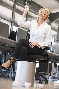 Businesswoman in office space throwing garbage in bin
