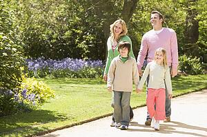 Family walking on path holding hands smiling