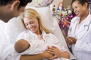 New parents with baby talking to doctor and smiling