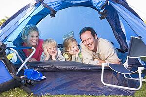 Family camping in tent smiling